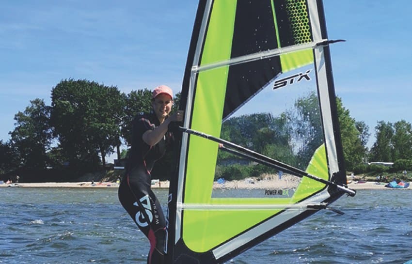 Eine Windsurferin mit grünem Segel vor dem Loissiner Strand